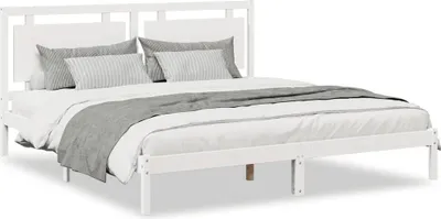 A white wooden bed frame with pillows and a blanket.