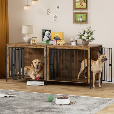 Two dogs are inside a large wooden dog crate furniture piece, which is set up in a living room environment. The crate has a table-like top surface with decorative items.