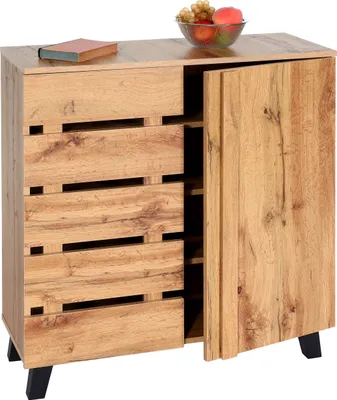 A wooden kommode with an open door, displaying shelves inside. A book and a bowl of fruit are on top.