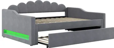 A gray upholstered daybed with a pull-out trundle bed, featuring green LED lighting on the side.