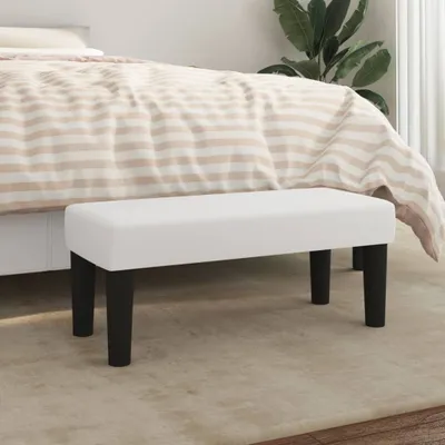 A white bench with black legs is placed in front of a bed with striped bedding.