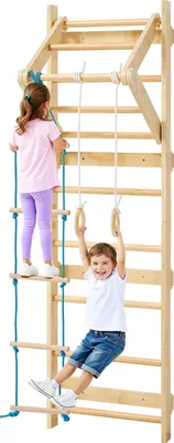 Two children are playing on a wooden climbing frame indoors.