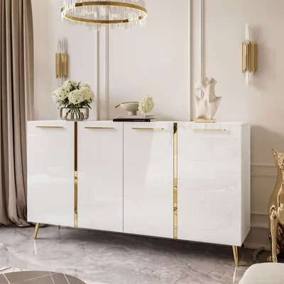 A white high-gloss sideboard with gold accents and legs, decorated with a vase of flowers and a sculpture.