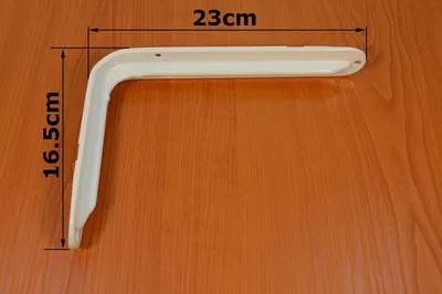 A white shelf bracket is shown on a wooden surface, with dimensions indicated by text and lines.