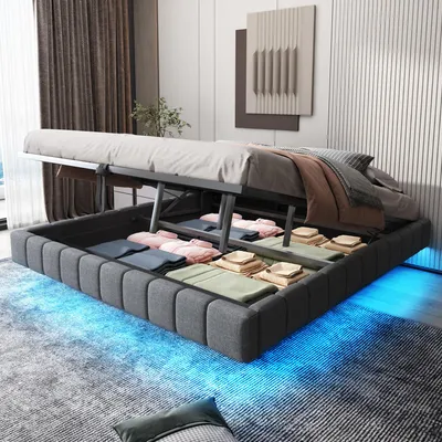 A bed with its storage compartment open, revealing folded linens and clothing, illuminated by blue LED lights underneath.