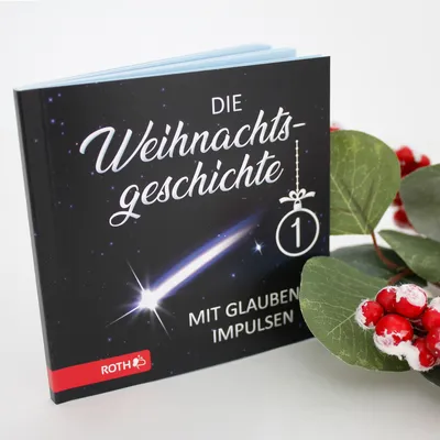 A book titled 'Die Weihnachtsgeschichte' with a comet and a Christmas ornament on the cover, placed next to some greenery with red berries.