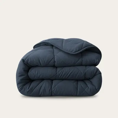 A folded dark blue comforter is shown against a white background.