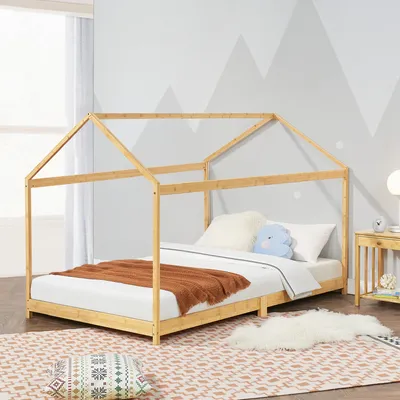 A child's bed with a house-shaped frame in a room with mountain-themed wallpaper.