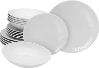 A stack of white porcelain plates and bowls with a ribbed texture.