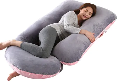 A woman is sleeping on a large U-shaped pregnancy pillow.