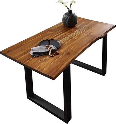 A wooden dining table with a live edge and black metal legs, set against a white background. A vase with flowers, a plate, and napkins are placed on the table.