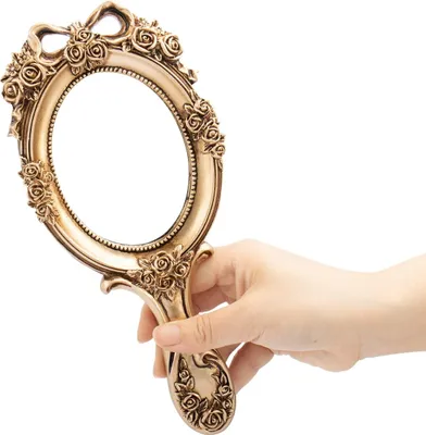 A hand holding a decorative hand mirror.