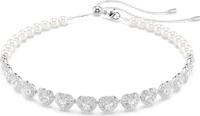 A close-up studio shot of a silver necklace with pearls and heart-shaped crystal pendants.