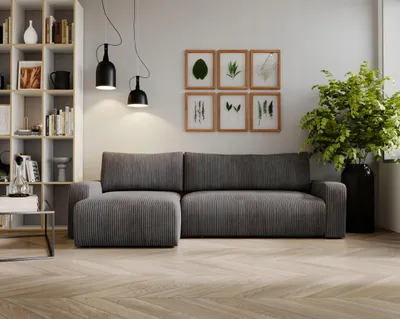 A modern living room with a grey sectional sofa, a bookshelf, and framed botanical prints.
