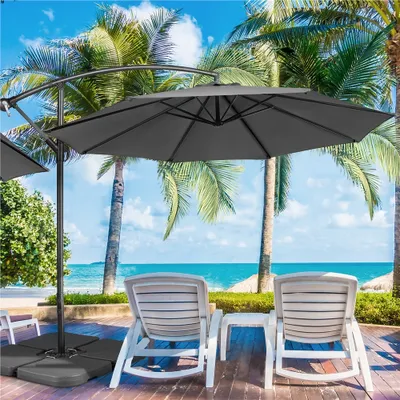 A patio scene with lounge chairs and a large umbrella overlooking the ocean.