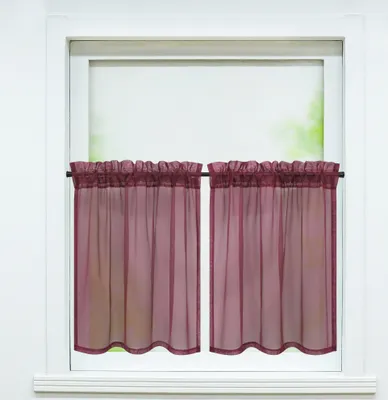 Two sheer burgundy curtains hang on a curtain rod in front of a window.