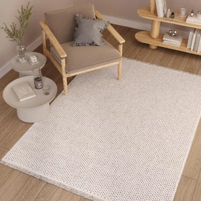 A modern living room setting with a chair, side tables, and a rug.