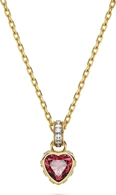 A gold necklace with a heart-shaped red pendant and clear stones.