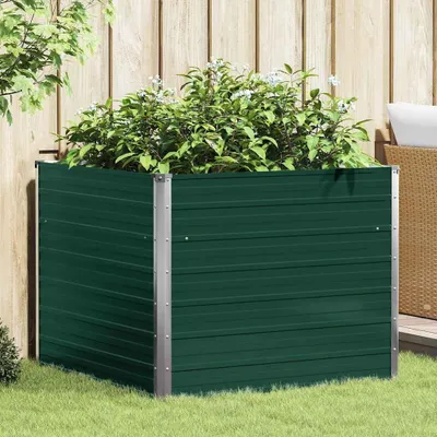 A green metal raised garden bed filled with plants, situated on a lawn in front of a wooden fence.