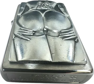 A close-up, angled view of a Zippo lighter with a sculpted design of a woman's buttocks.