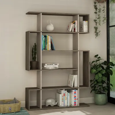 A modern, asymmetric bookshelf filled with books and decorative items, placed in a room with natural light coming from a window.