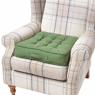 A green cushion placed on a checkered armchair.