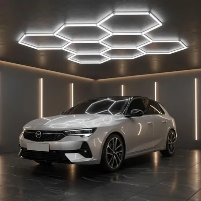 A white car is parked in a modern garage with hexagonal ceiling lights and vertical strip lights on the walls.