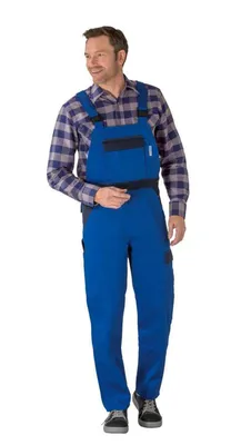 A man wearing blue overalls and a plaid shirt stands against a white background.