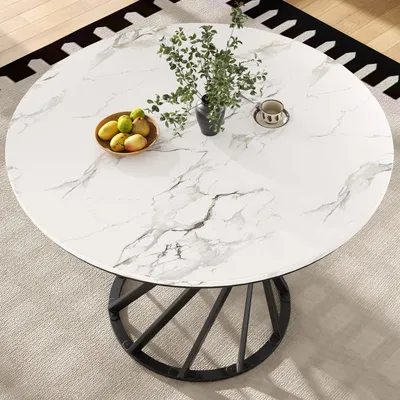 A round marble-top dining table with a black metal base, set on a rug.
