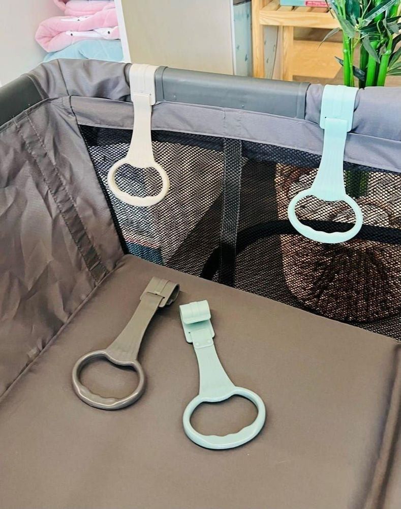 Poignées SUN BABY installées sur le rebord d'un parc, prêtes à l'emploi pour un bébé.