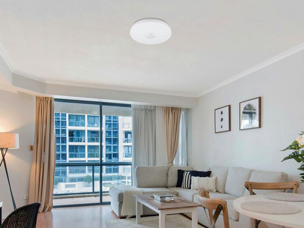 Deckenleuchte als zentraler Punkt des Wohnzimmers, helles Interieur mit Sofa und Couchtisch.