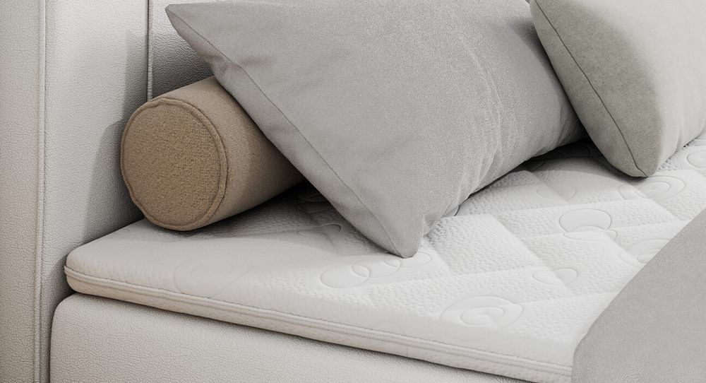 Gestepptes Kopfteil eines weiß Bettes. Eine Topper-Matratze liegt auf dem Bett