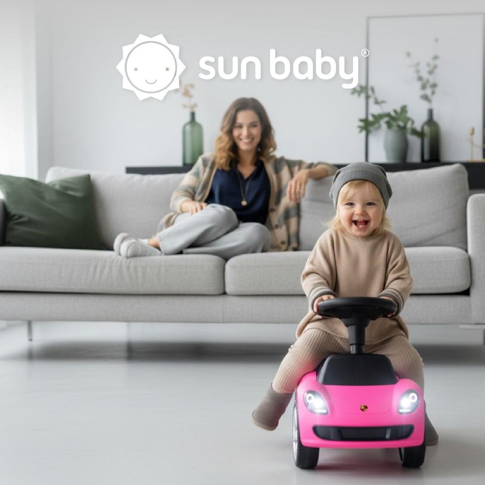 Kind fährt das Rutschauto im Wohnzimmer, Mutter im Hintergrund auf dem Sofa sichtbar