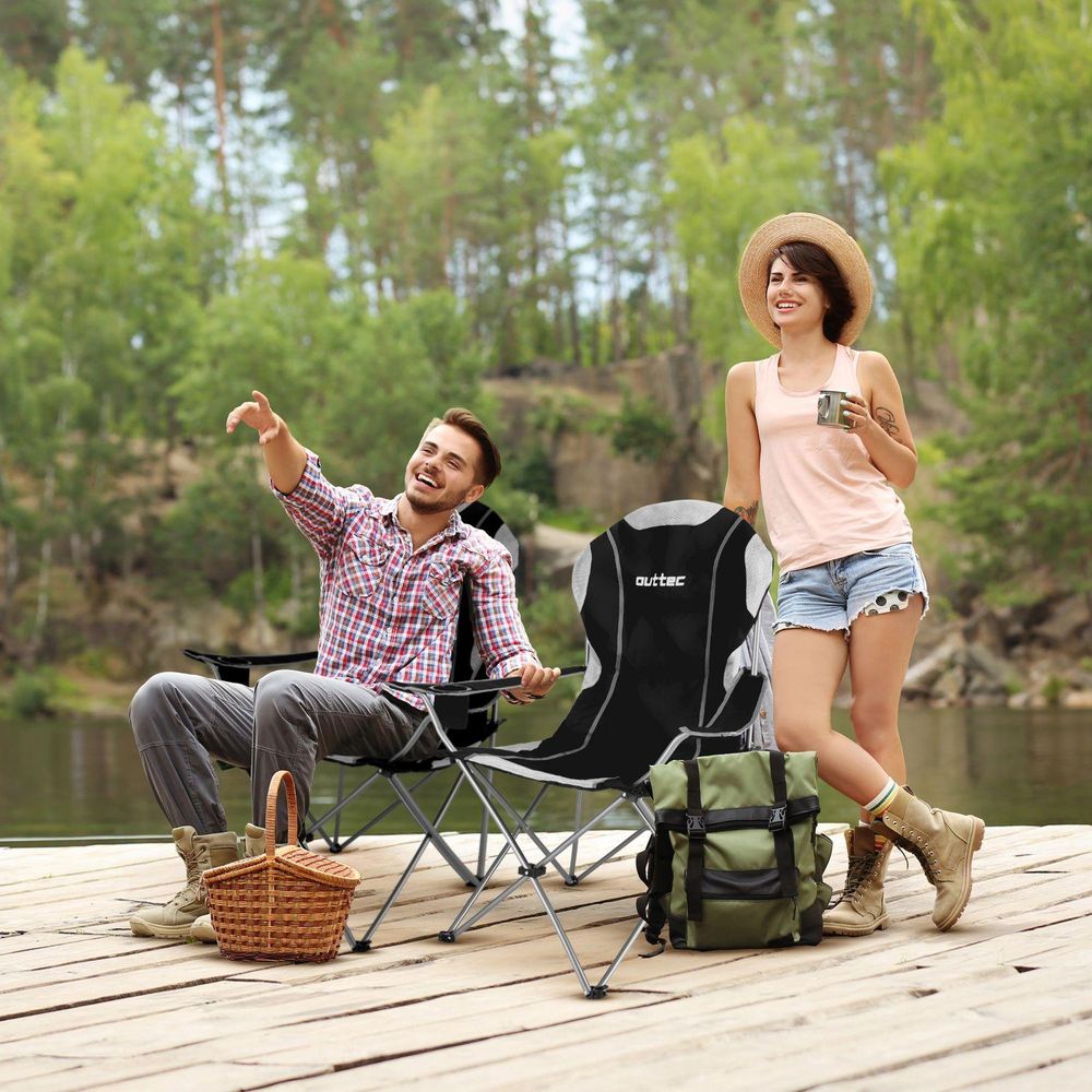 Paar sitzt auf Campingstühlen am See und genießt die Natur