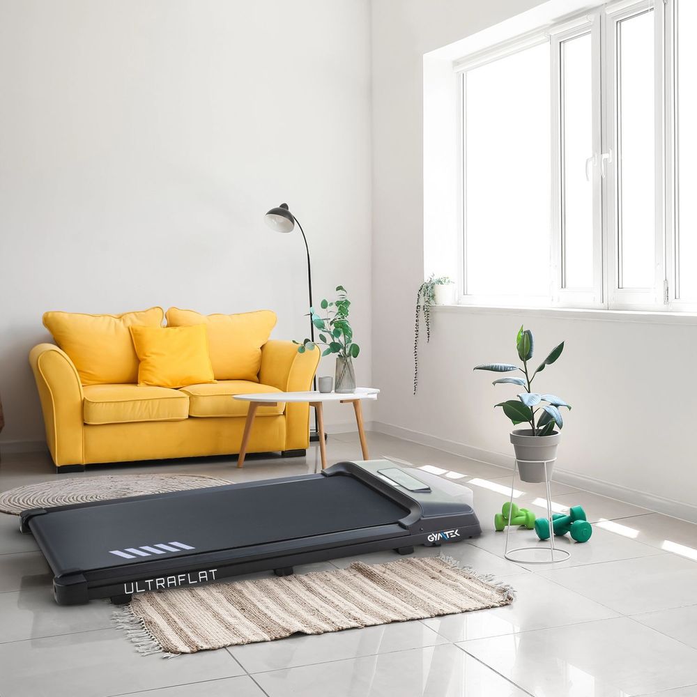 Kompaktes Laufband in einem modernen Wohnraum mit gelbem Sofa.
