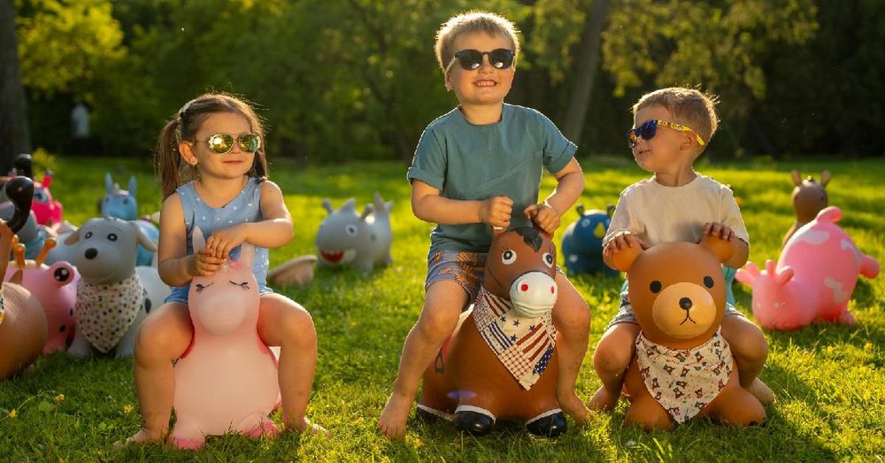 Niños jugando con animales saltarines en el césped al aire libre.