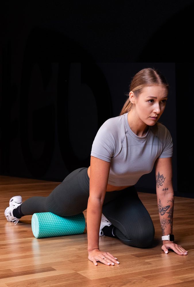 Trening Fitness z wałkiem do masażu z wypustkami 30x15 cm FIZYO — osoba wykonuje ćwiczenia
