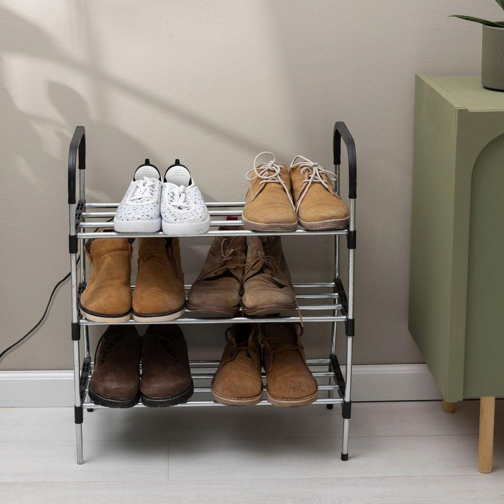 Schuhregal aus Metall, gefüllt mit Schuhen. Ein Schuhtrockner ist in einem Paar zu sehen