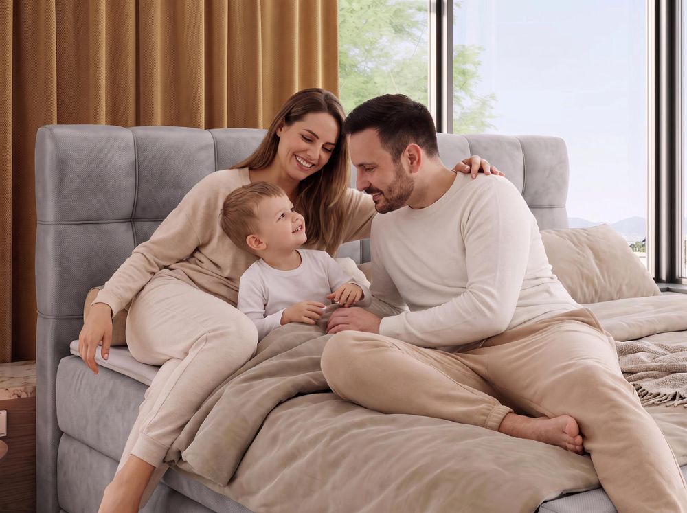 Graues Polsterbett mit Familie und beiger Bettwäsche im hellen Schlafzimmer.