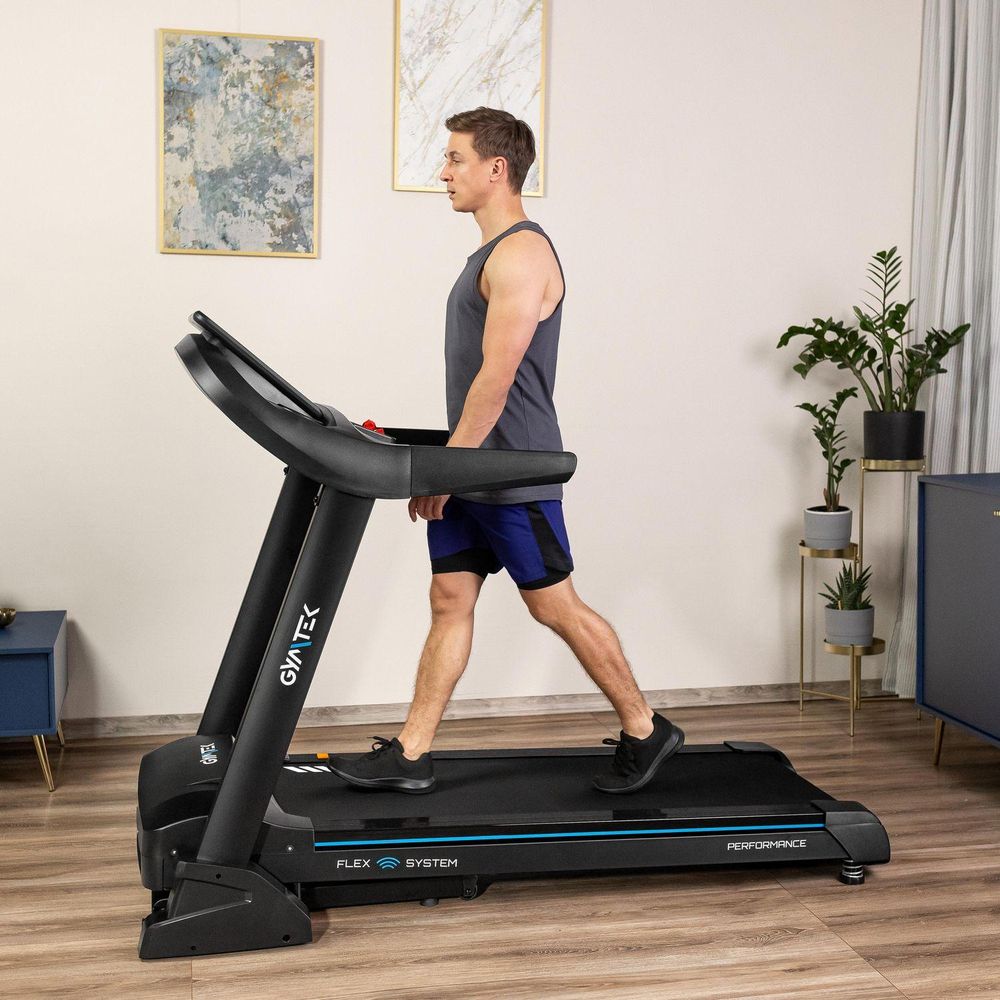 Mann geht entspannt auf einem schwarzen GYMTEK Laufband in einem hellen Raum