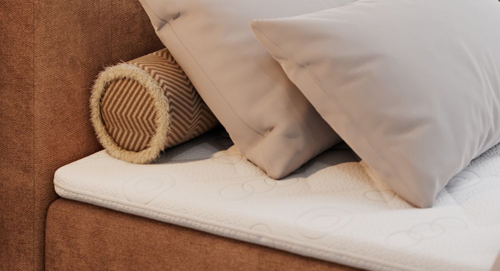 Gestepptes Kopfteil eines orange Bettes. Eine Topper-Matratze liegt auf dem Bett