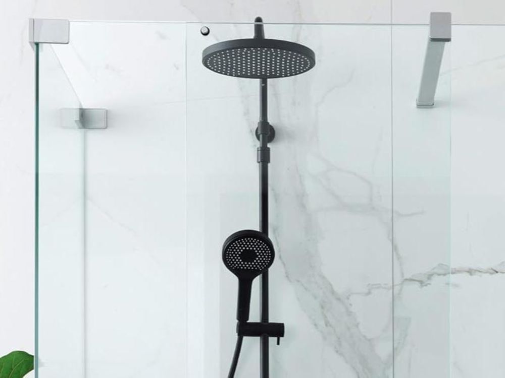 Modernes schwarzes Duschsystem BIELLA mit Kopfbrause und Handbrause vor heller Marmorwand