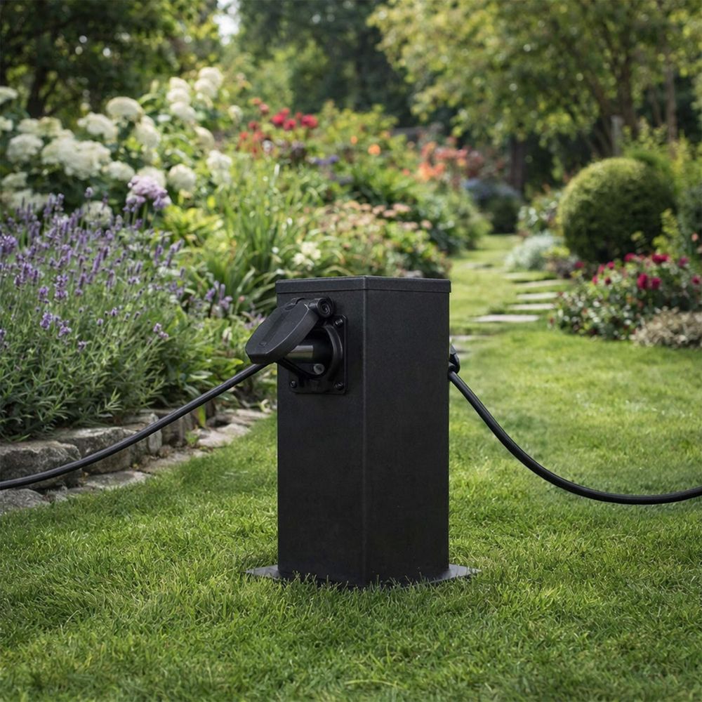Schwarzer Gartenpfosten mit Steckdosen auf dem Rasen, Nahaufnahme, Kabel angeschlossen.