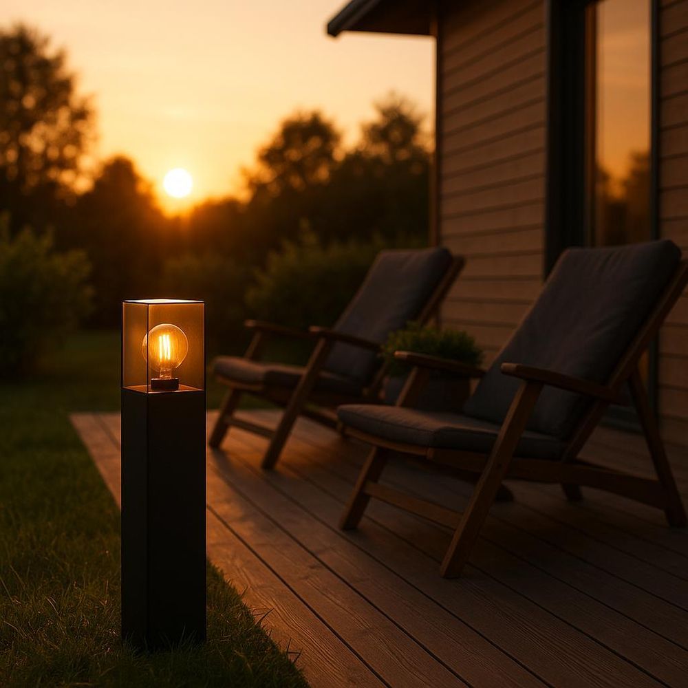 Moderne Außenleuchte mit Glas und sichtbarer Glühbirne auf Terrasse bei Sonnenuntergang platziert.