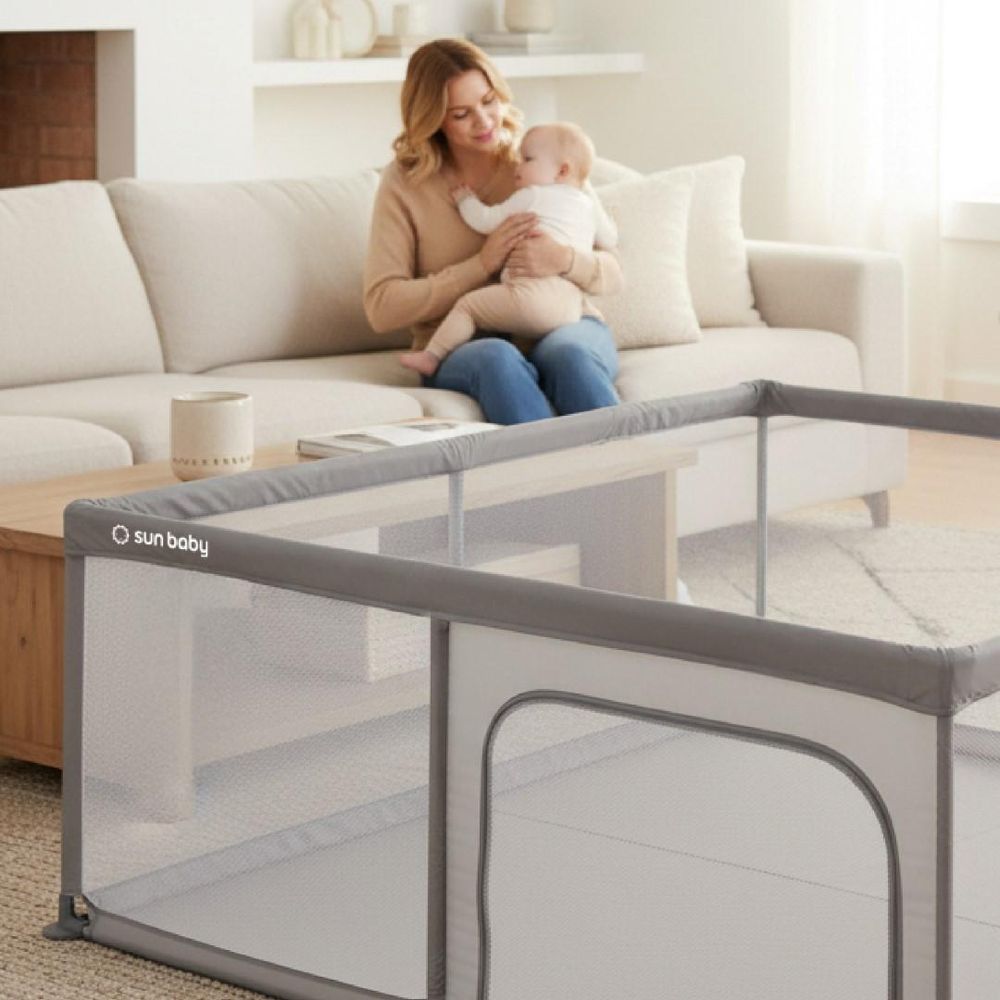 Close-up van bovenrand kinderbox met vrouw en baby op de achtergrond