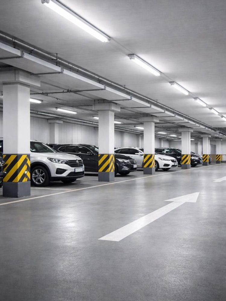 Das Bild zeigt eine Tiefgarage mit Autos in neutralweißem Licht.