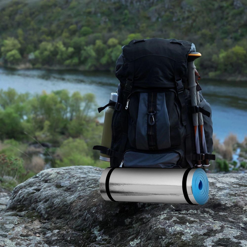 Gerollte, silberne Isomatte an Rucksack, bereit für Wanderungen in der Natur