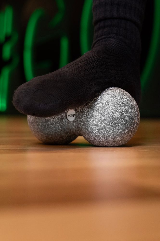 Osoba ćwicząca i wykorzystująca piłkę do masażu duoball FIZYO 16x8 cm