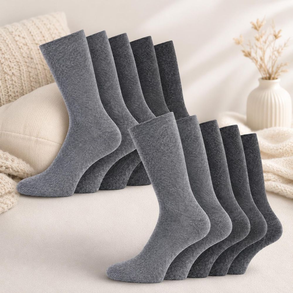 Zehn graue Herrensocken in verschiedenen Grautönen dekorativ auf einem hellen Sofa präsentiert
