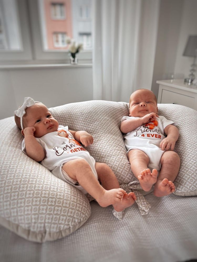 Deux jumeaux allongés naissant sur un coussin d'allaitement pour jumeaux.